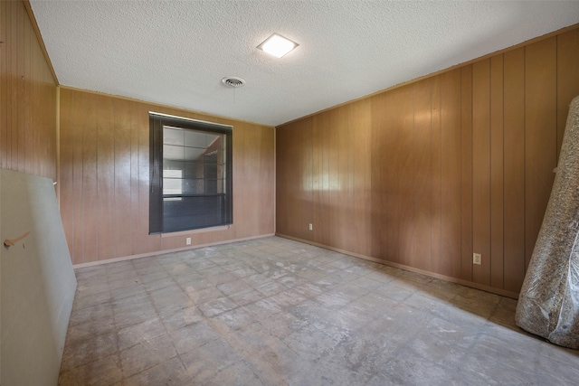 tiled spare room featuring wood walls and a textured ceiling