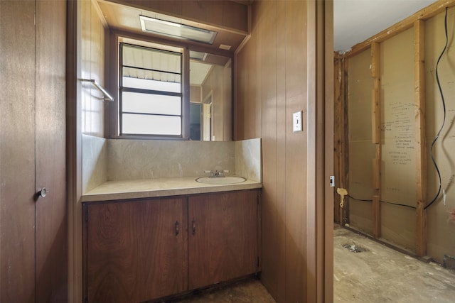 bathroom with wood walls, oversized vanity, and concrete floors