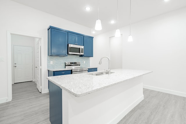 kitchen with appliances with stainless steel finishes, a kitchen island with sink, sink, blue cabinetry, and decorative light fixtures