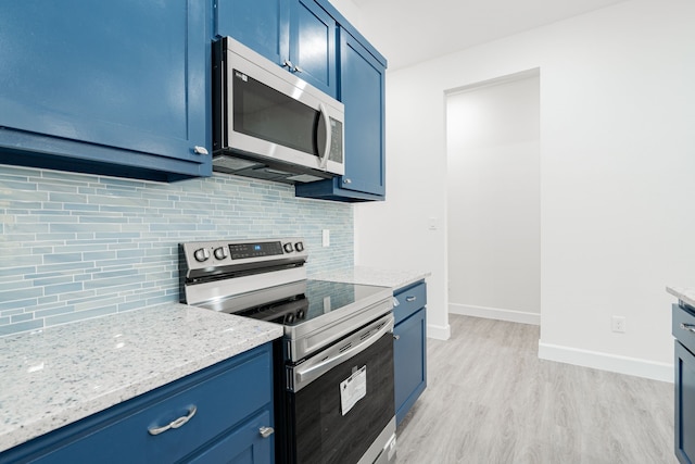 kitchen with decorative backsplash, blue cabinetry, appliances with stainless steel finishes, light hardwood / wood-style floors, and light stone counters