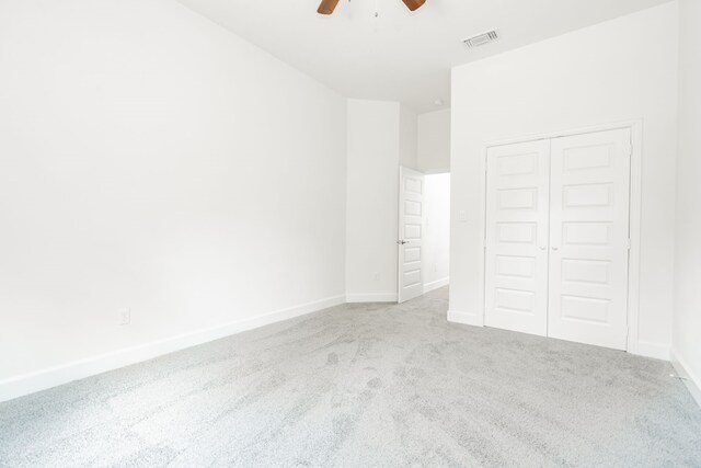 unfurnished bedroom with ceiling fan, light colored carpet, and a closet