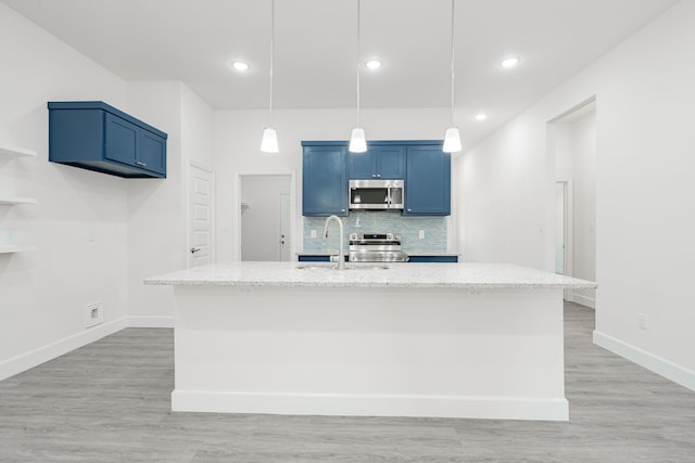 kitchen with pendant lighting, stainless steel appliances, and an island with sink