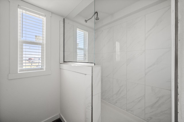 bathroom with a tile shower and a healthy amount of sunlight