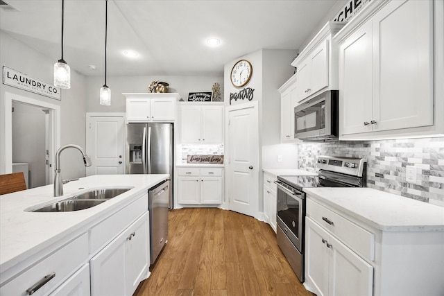 kitchen with hanging light fixtures, white cabinetry, sink, and stainless steel appliances