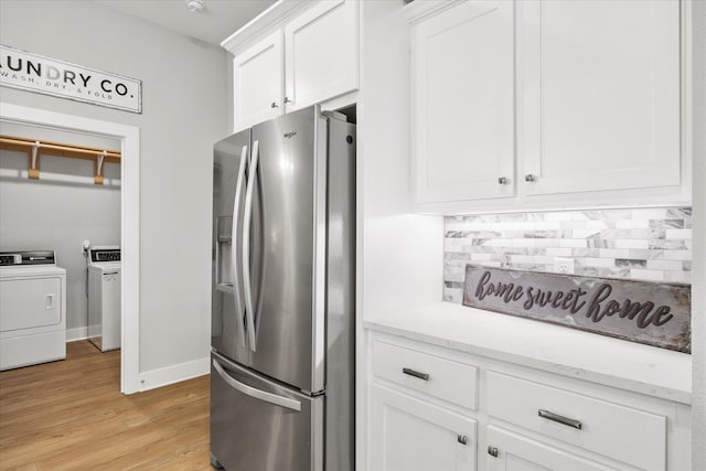 kitchen featuring light hardwood / wood-style flooring, stainless steel fridge with ice dispenser, separate washer and dryer, light stone counters, and white cabinetry