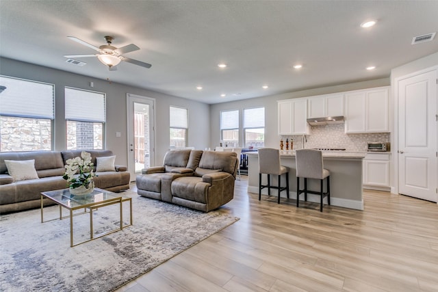 living room with ceiling fan and light hardwood / wood-style flooring