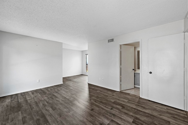 unfurnished room with a textured ceiling and dark hardwood / wood-style flooring