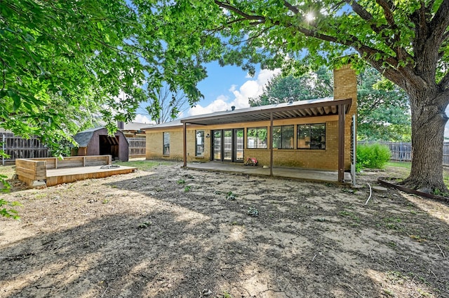 rear view of house with a storage shed and a patio