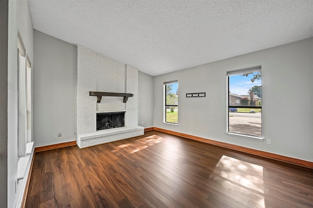 unfurnished living room with a textured ceiling, a fireplace, and dark hardwood / wood-style flooring