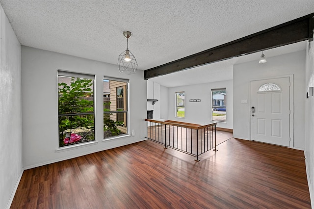 foyer with beamed ceiling, dark hardwood / wood-style floors, and a textured ceiling