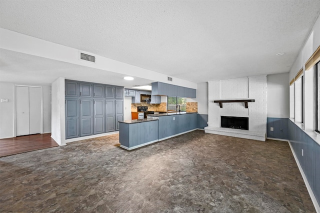 unfurnished living room with a brick fireplace, a textured ceiling, and sink