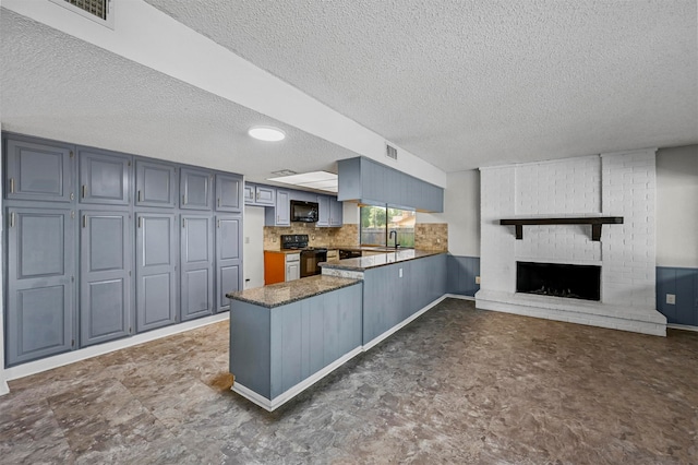 kitchen with black appliances, sink, kitchen peninsula, a fireplace, and a textured ceiling