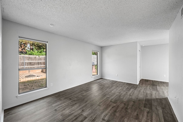 unfurnished room featuring a healthy amount of sunlight, dark wood-type flooring, and a textured ceiling