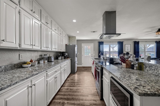 kitchen featuring white cabinets, stainless steel appliances, a healthy amount of sunlight, and range hood