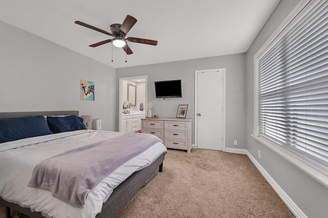 bedroom with ceiling fan, light colored carpet, and ensuite bathroom