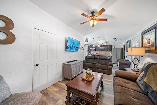 living area featuring vaulted ceiling, light wood-type flooring, brick wall, and ceiling fan