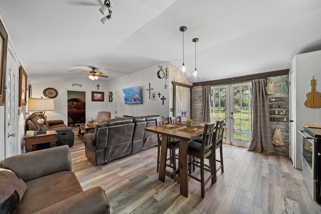 dining area with a ceiling fan, vaulted ceiling, light wood-style floors, and french doors