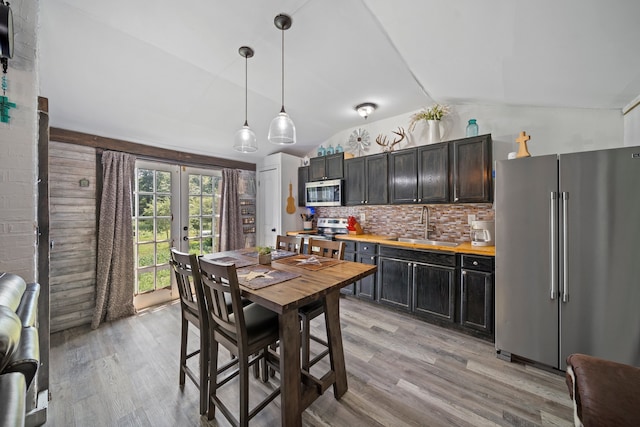 dining room with light wood finished floors, french doors, and vaulted ceiling