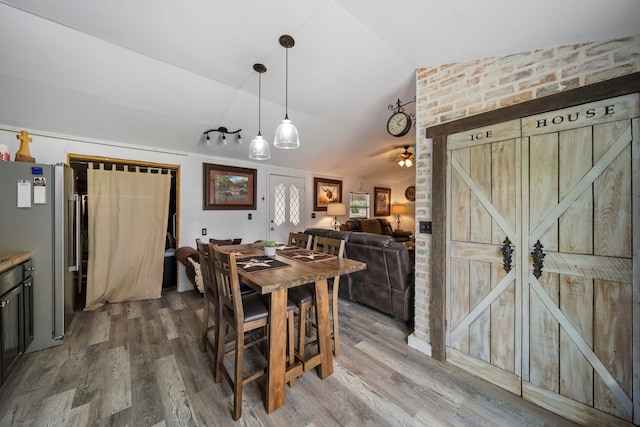 dining space with lofted ceiling, a barn door, wood finished floors, and ceiling fan