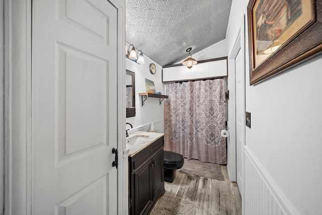 bathroom with vanity, a textured ceiling, wood-type flooring, lofted ceiling, and toilet