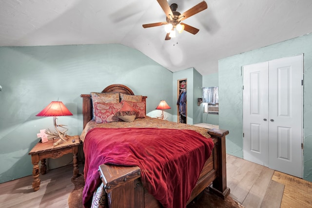 bedroom with a ceiling fan, wood finished floors, vaulted ceiling, a closet, and a walk in closet