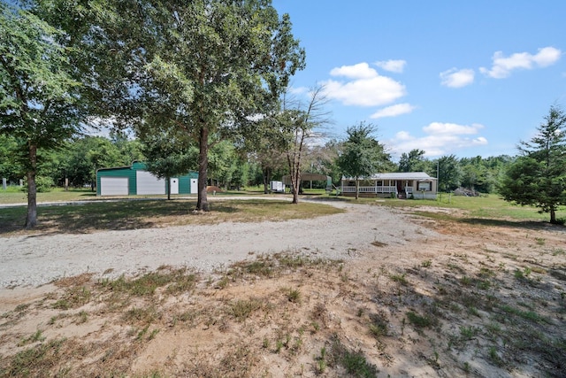 view of yard with a detached garage, an outbuilding, and driveway