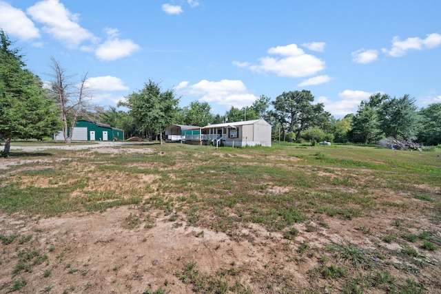 view of yard featuring a carport, a detached garage, and an outdoor structure