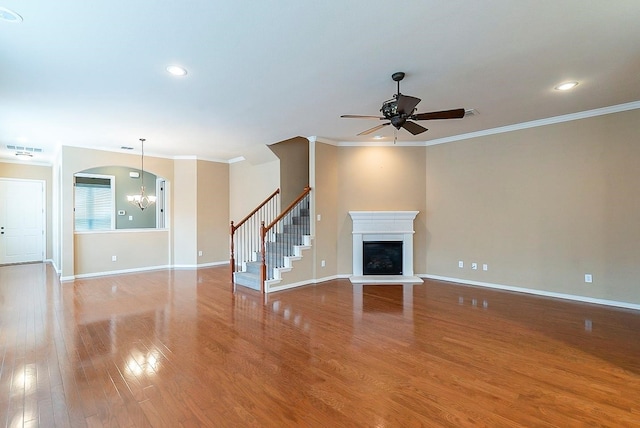 unfurnished living room with light wood-type flooring, ceiling fan with notable chandelier, and crown molding