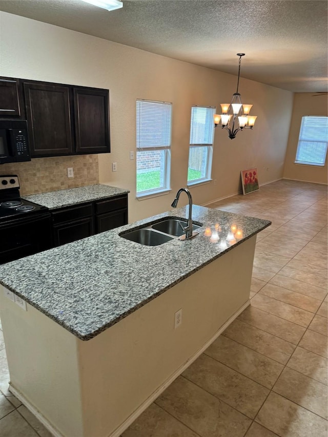 kitchen with an island with sink, light stone countertops, sink, and black appliances