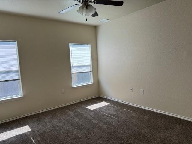 empty room featuring ceiling fan and dark carpet