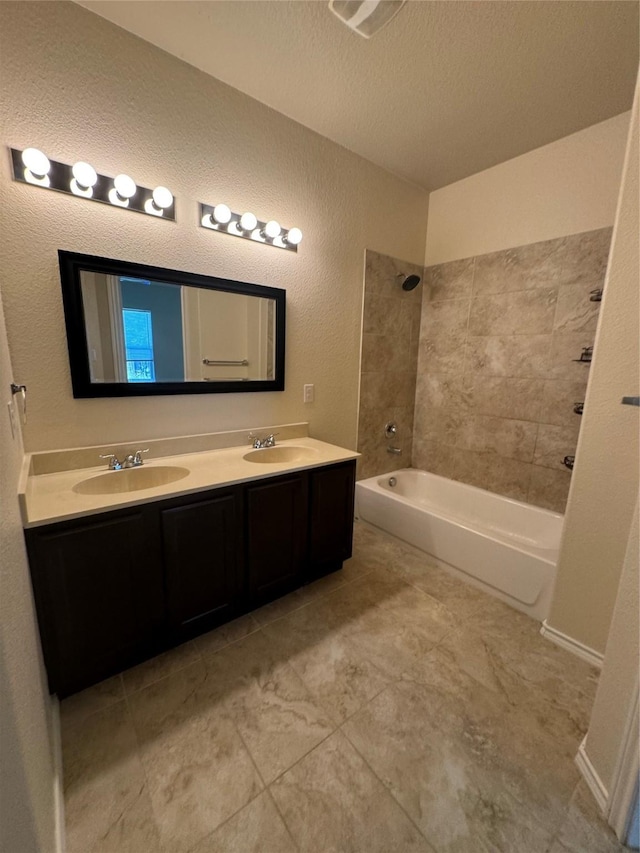 bathroom with tiled shower / bath, vanity, and a textured ceiling