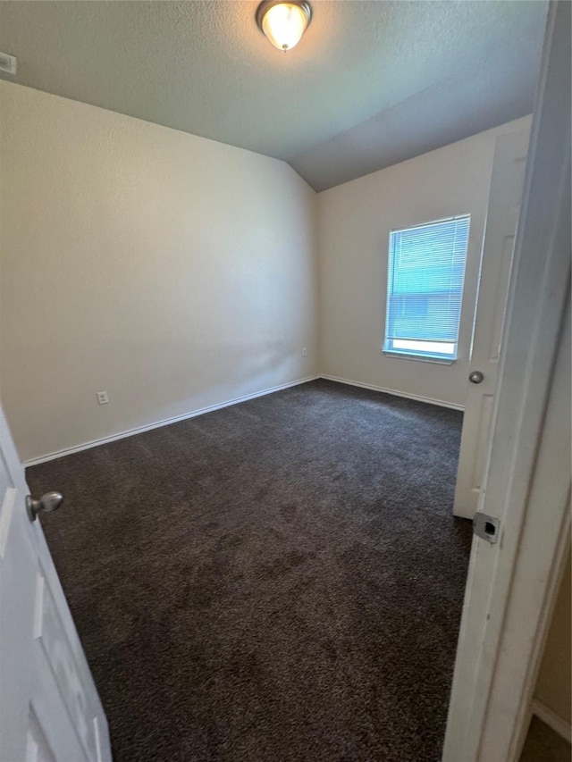 carpeted spare room featuring lofted ceiling and a textured ceiling