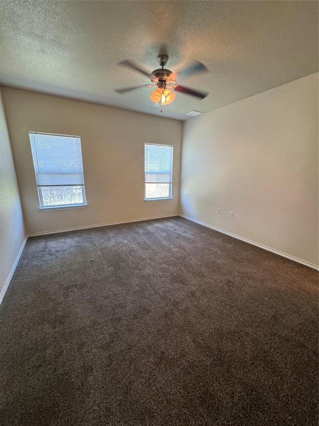 spare room featuring a textured ceiling, ceiling fan, and dark colored carpet