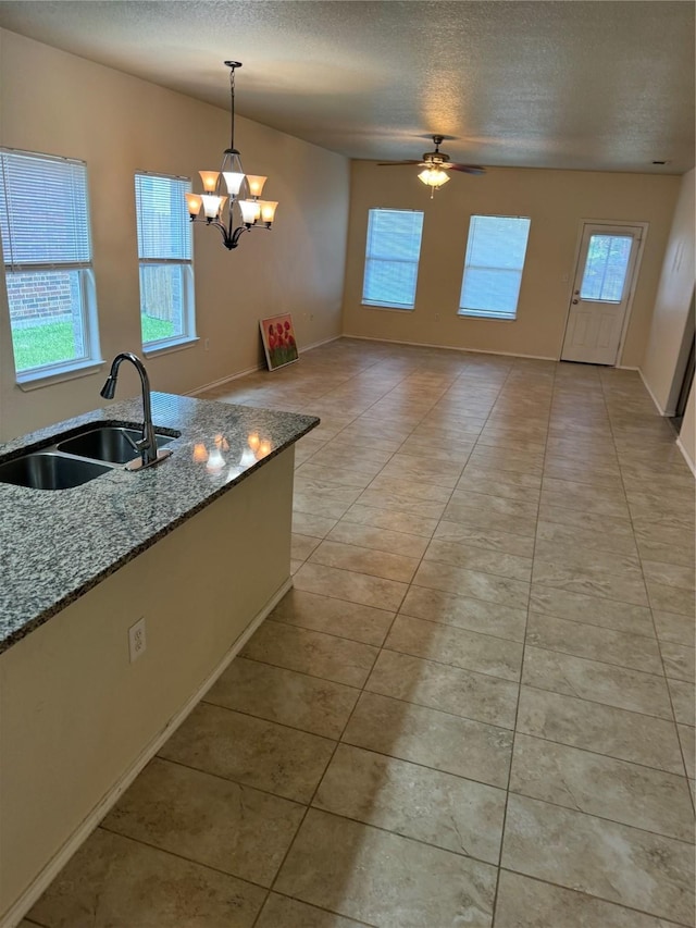 kitchen featuring pendant lighting, sink, light tile patterned floors, light stone counters, and a textured ceiling