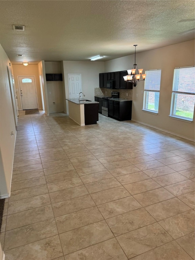 kitchen featuring stainless steel electric range oven, sink, light tile patterned floors, a notable chandelier, and a center island with sink