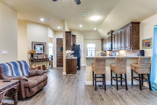 kitchen featuring a breakfast bar, lofted ceiling, kitchen peninsula, stainless steel appliances, and light hardwood / wood-style flooring