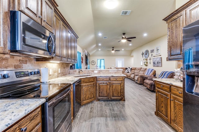 kitchen featuring sink, vaulted ceiling, appliances with stainless steel finishes, light hardwood / wood-style floors, and backsplash