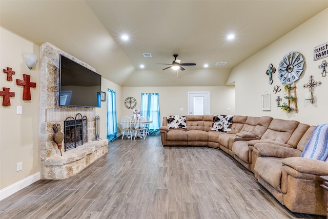 living room featuring wood-type flooring, vaulted ceiling, ceiling fan, and a fireplace