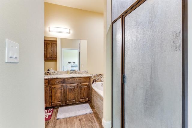 bathroom featuring vanity, tiled tub, and hardwood / wood-style flooring