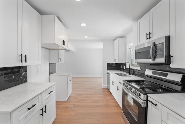 kitchen featuring light hardwood / wood-style floors, sink, stainless steel appliances, and white cabinetry