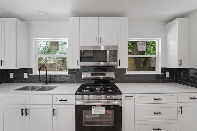 kitchen with light stone countertops, sink, white cabinetry, and appliances with stainless steel finishes