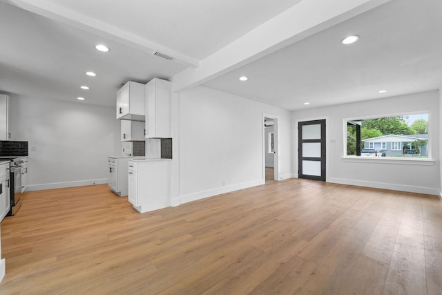 kitchen with white cabinets, beamed ceiling, tasteful backsplash, stainless steel stove, and light wood-type flooring