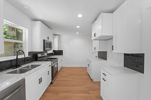 kitchen with stainless steel appliances, light hardwood / wood-style flooring, white cabinetry, and sink