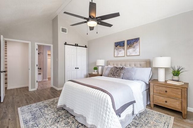 bedroom featuring a barn door, hardwood / wood-style flooring, a closet, and ceiling fan