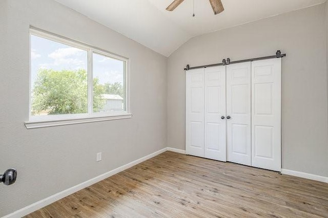 unfurnished bedroom with ceiling fan, light hardwood / wood-style flooring, and lofted ceiling