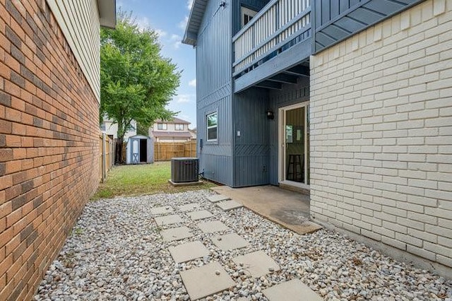 view of patio / terrace with a balcony, a shed, and central air condition unit