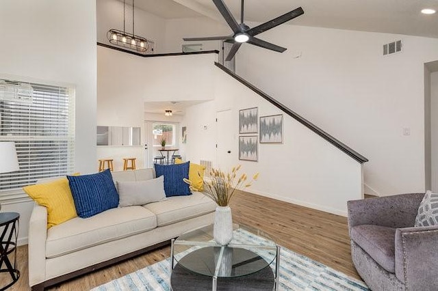 living room featuring high vaulted ceiling, light hardwood / wood-style floors, and ceiling fan with notable chandelier