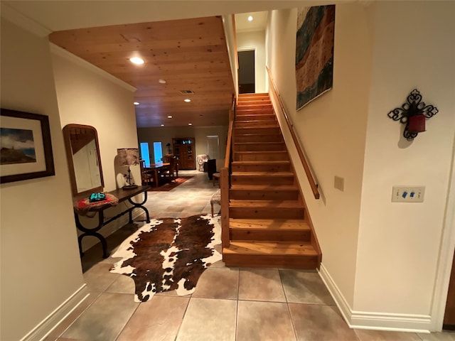 stairs with tile floors, wood ceiling, and crown molding