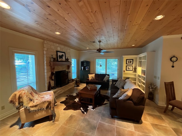 tiled living room with a stone fireplace, ceiling fan, wood ceiling, and plenty of natural light