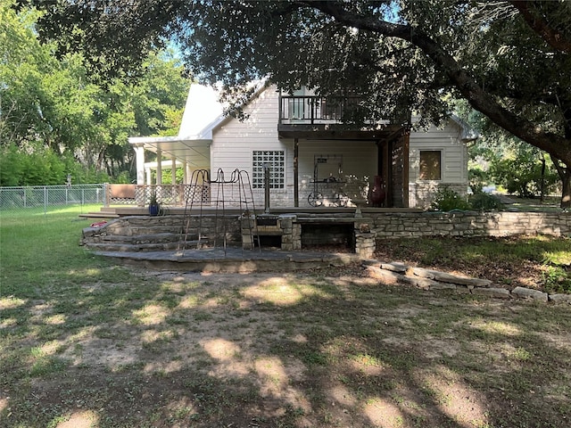 back of property with a balcony, fence, and a yard